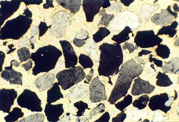 A thin film slice of rock shows grains loosely packed, displaying high porosity